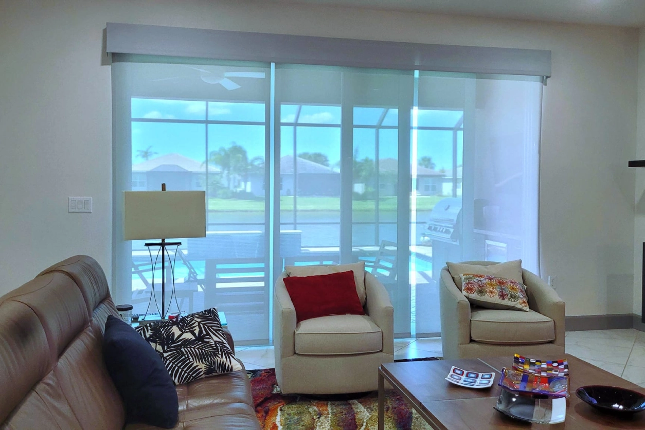 A living room with white furniture and sliding glass doors.