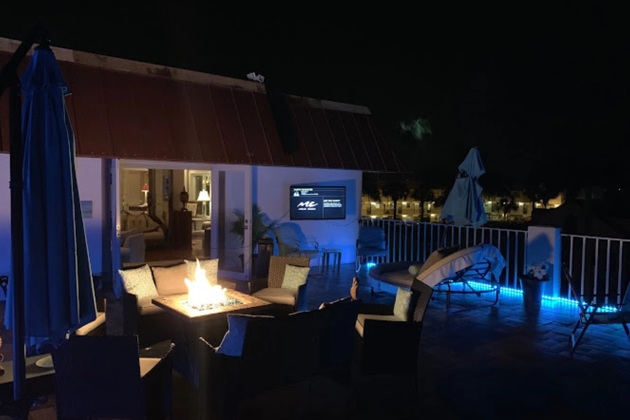 A patio with chairs and fire pit at night.