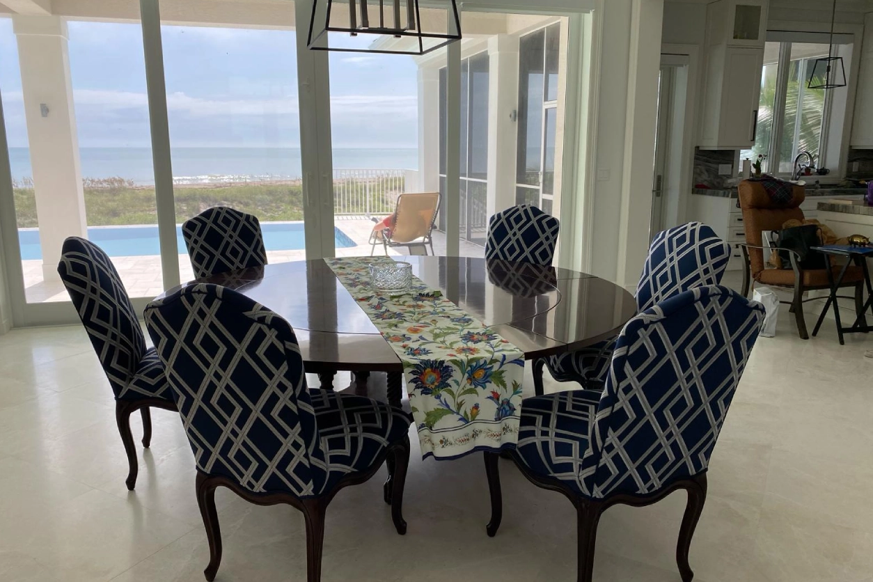 A dining room table with four chairs and a pool in the background.