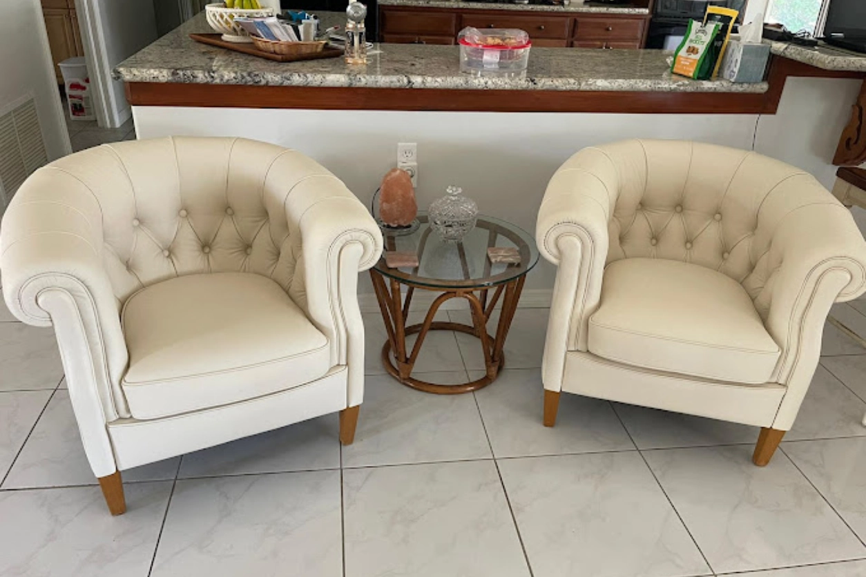 Two white chairs and a table in front of a bar.